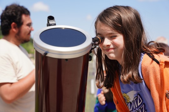 A girl looking through a solar telescope.